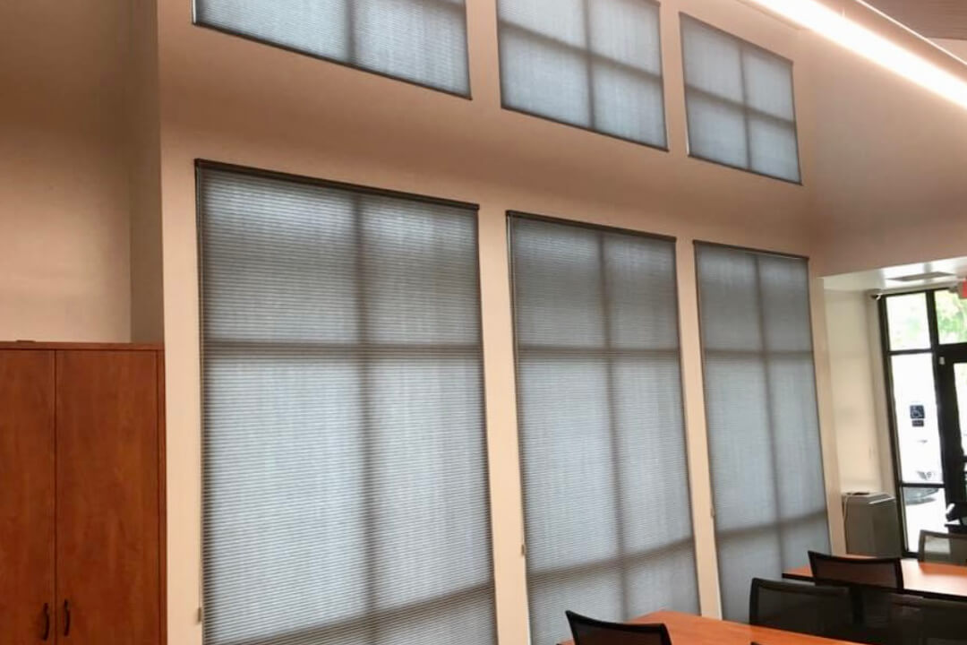 A classroom with many windows covered with roller shades.