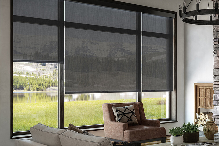 A living room in a house near the mountains with half-opaque roller blinds covering the windows mid-way.