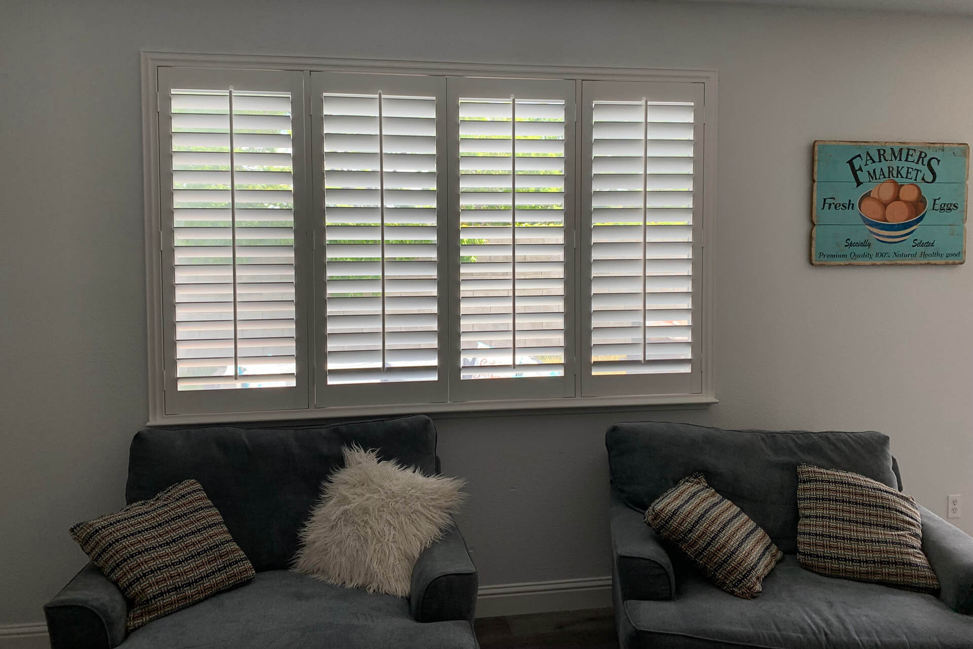 A seating area with two comfy chairs and a window covered by shutters.