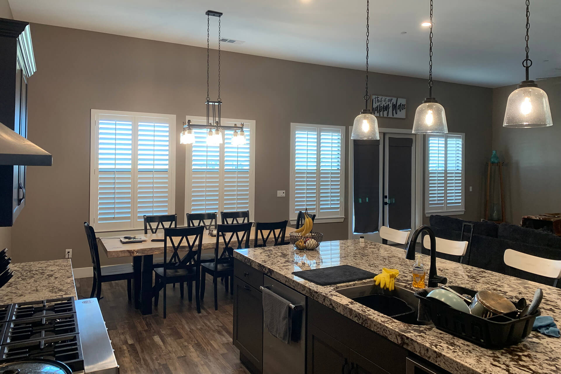 A large monochrome themed kitchen with a high ceiling that has shutters on four large windows.