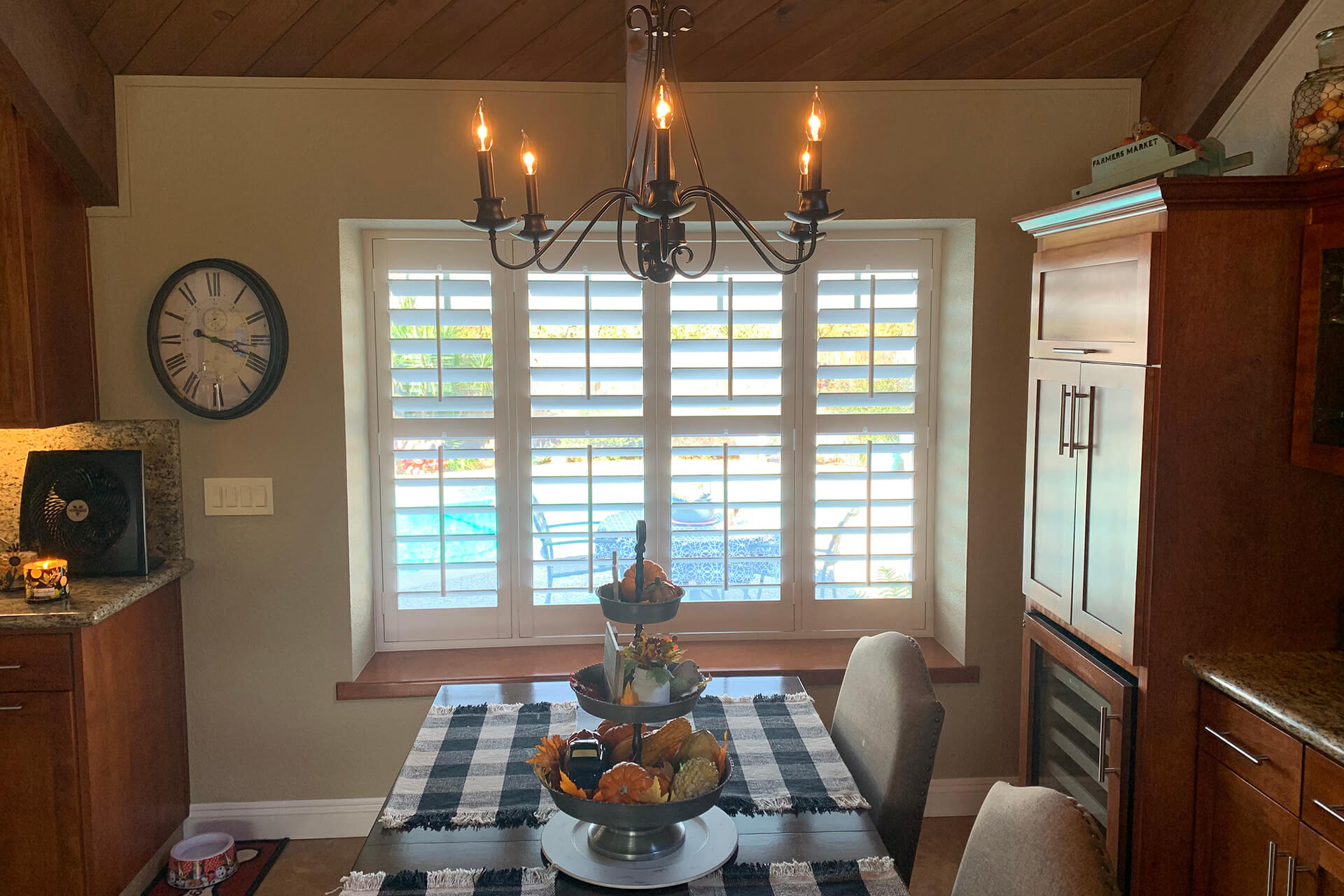 A wooden dining room with shutters covering the window to the backyard.